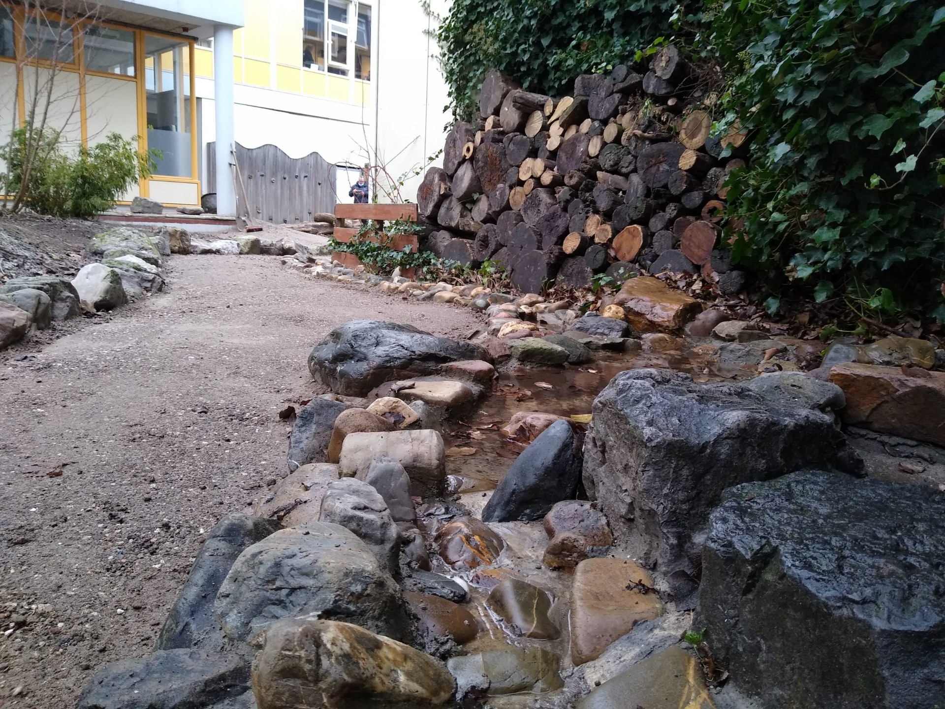 Stenen waterloop met keien langs een schoolgebouw