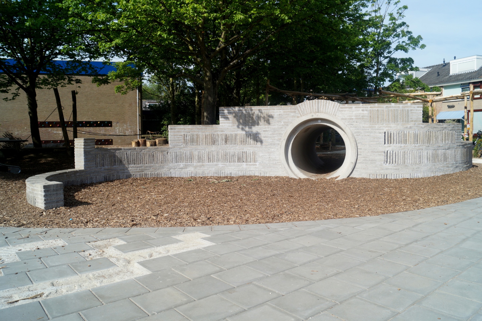 Podium met kruiptunnel op groen schoolplein