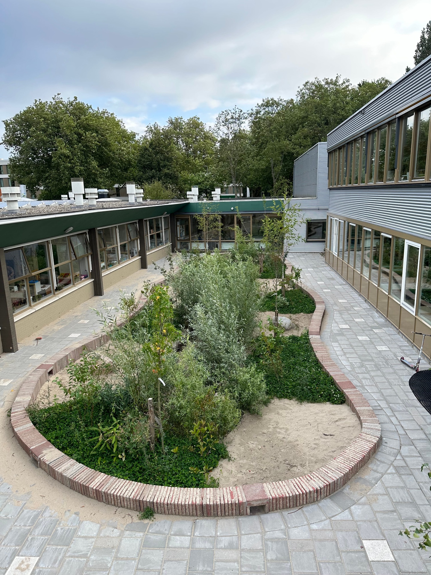 Wadi met beplanting tussen schoolgebouwen