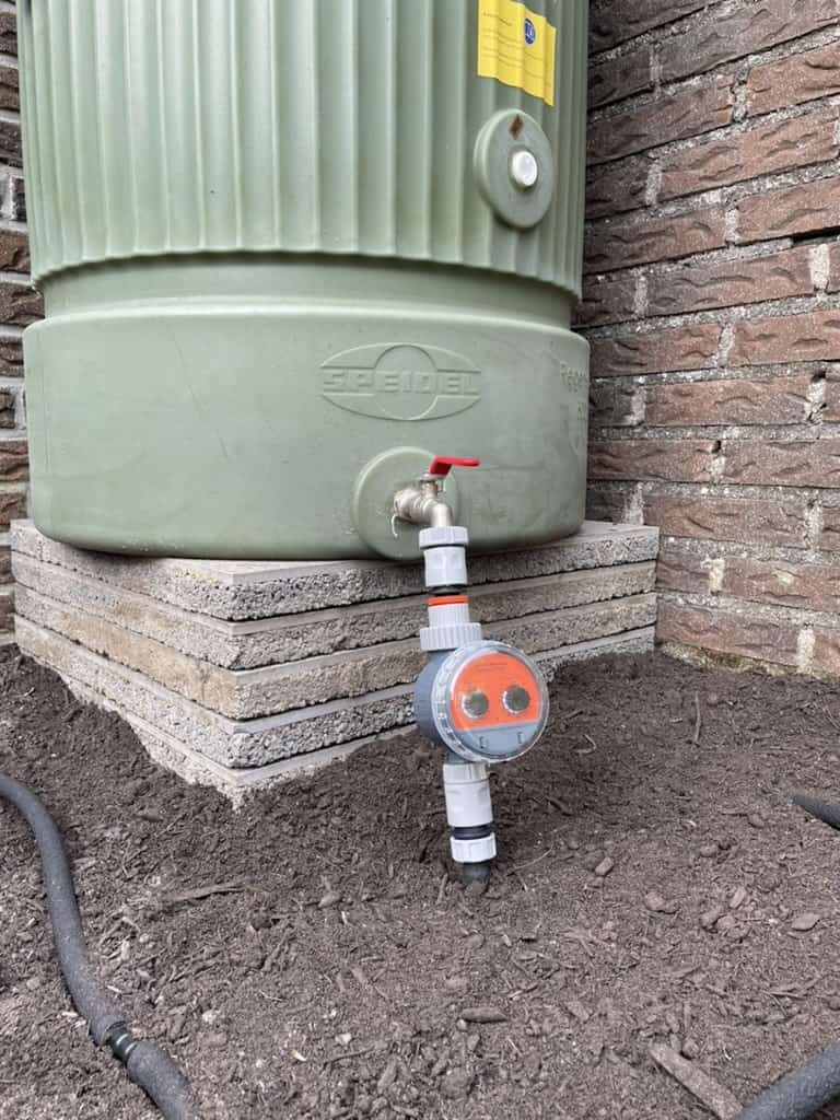 Verhoogde regenwatertank op stenen onderstel