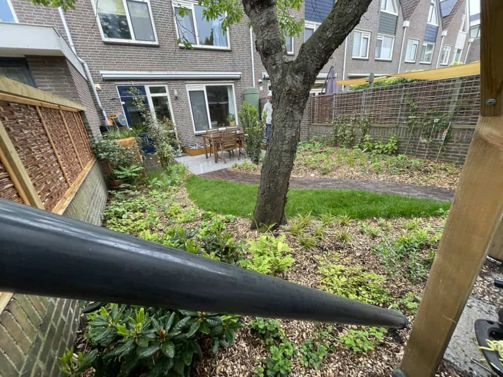 Tuin met boom, groene beplanting en zithoek