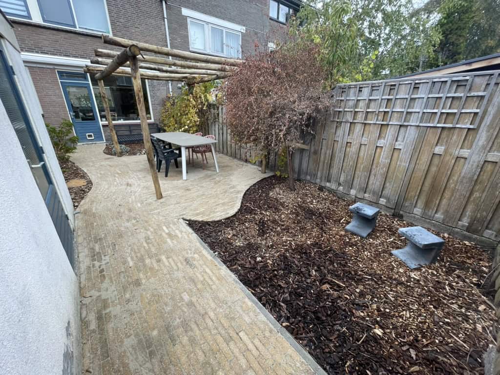 Tuin met houten overkapping en gevarieerde beplanting