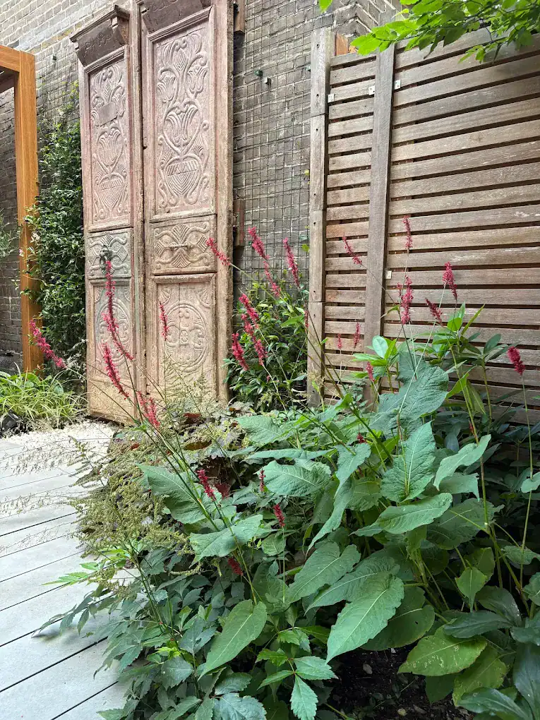 Houten tuinwand met roze bloeiende beplanting
